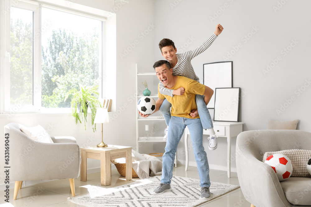 Little boy with soccer ball and his father at home