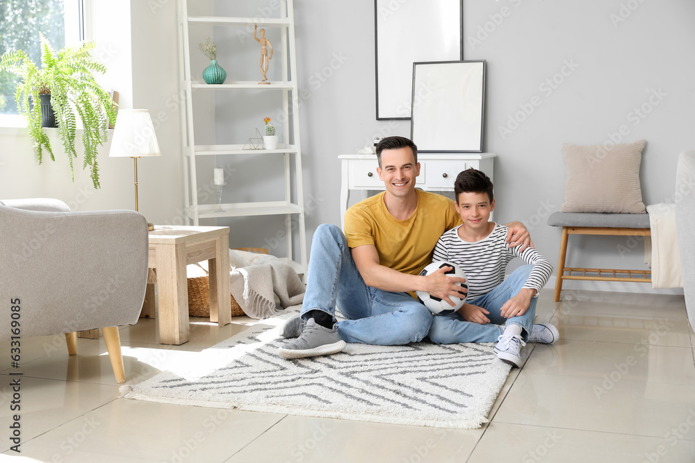 Little boy with soccer ball and his father at home