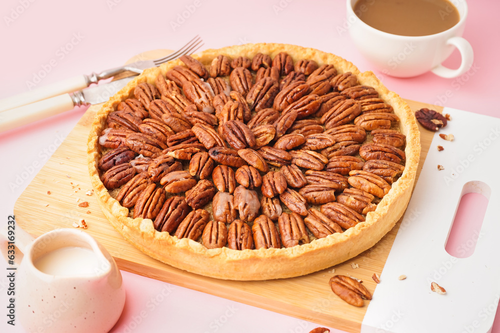 Wooden board with tasty pecan pie on pink background