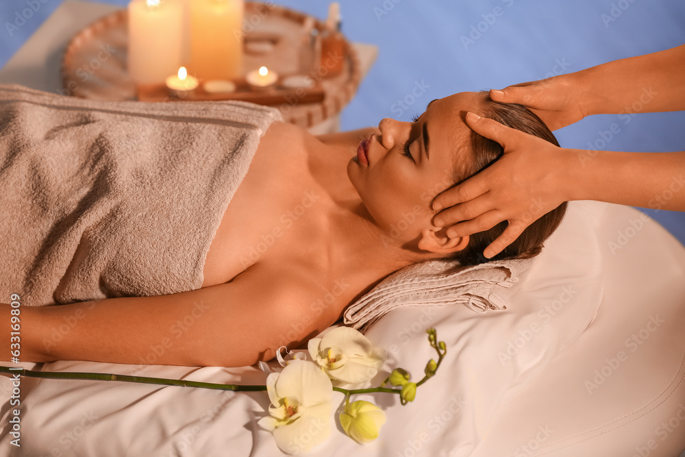 Pretty young woman having face massage in spa salon