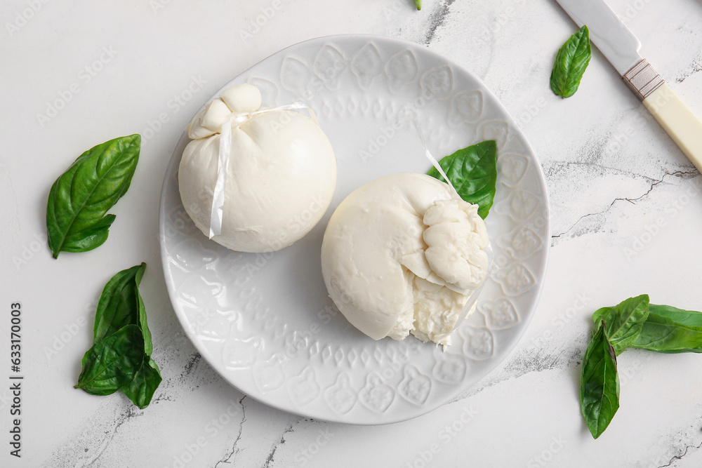 Plate of tasty Burrata cheese with basil on white background