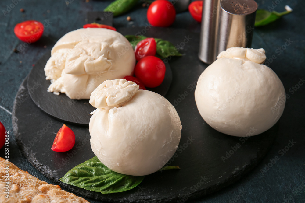 Board of tasty Burrata cheese with basil and tomatoes on dark background