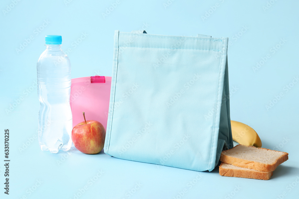 Bag, lunchbox with delicious food and bottle of water on blue background