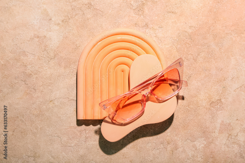 Decorative podiums with stylish sunglasses on orange background