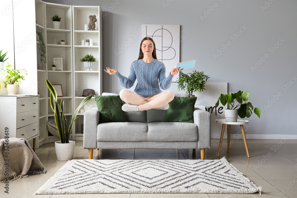 Flying young woman with book over sofa at home