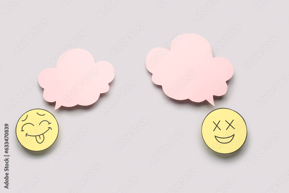 Paper faces with blank speech bubbles on grey background