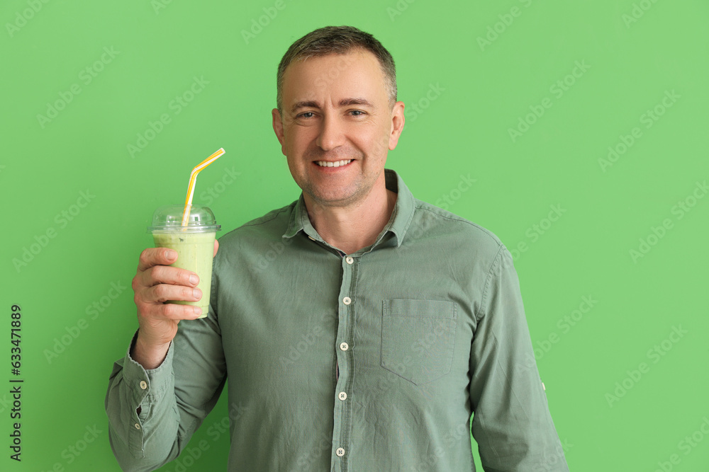 Mature man with glass of vegetable smoothie on green background