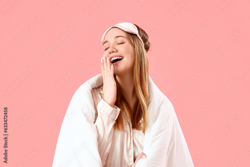 Young woman with sleeping mask and blanket on pink background