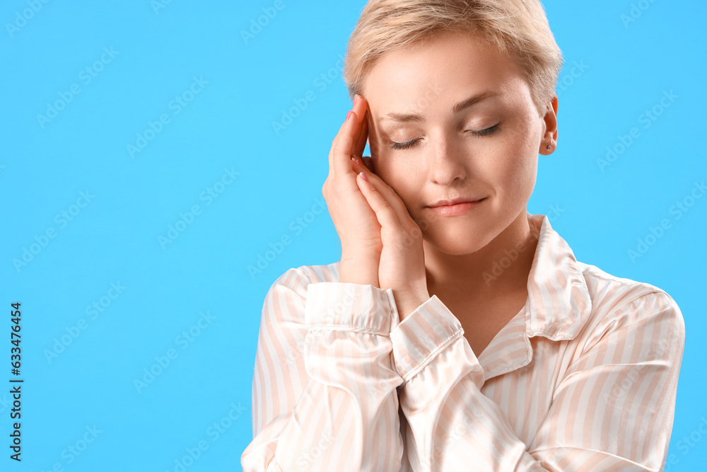 Young woman in pajamas on blue background, closeup