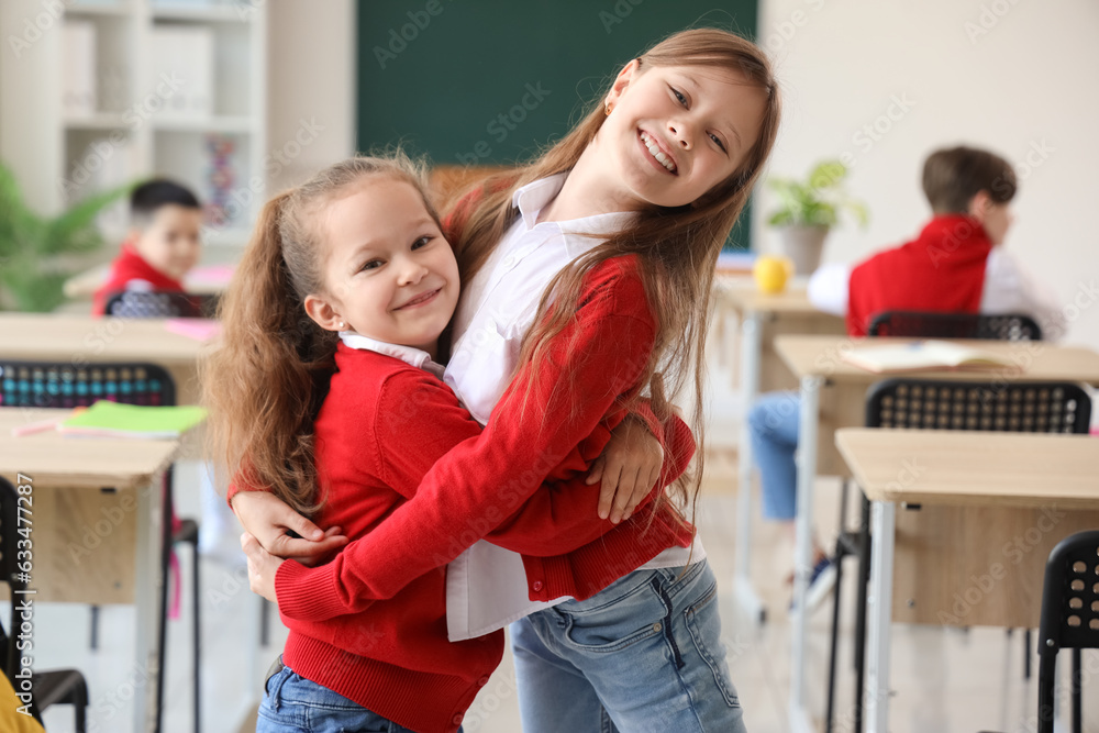 Happy little girls hugging in classroom