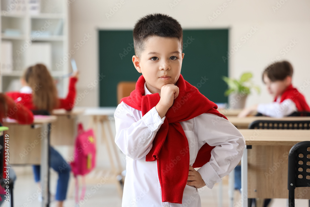 Thoughtful little schoolboy in classroom