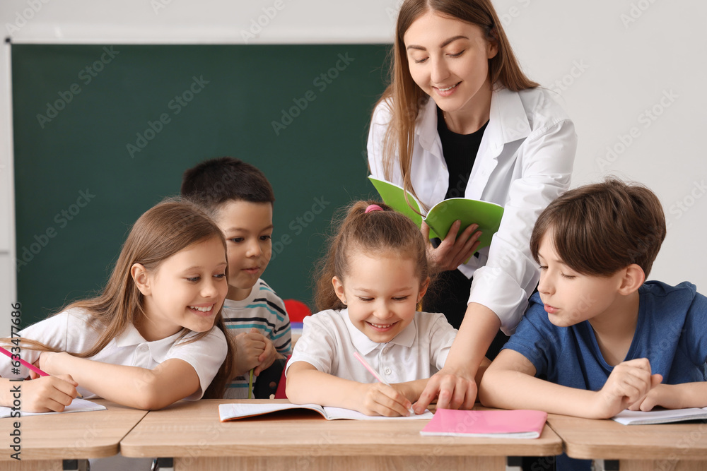 Little pupils having lesson with teacher in classroom