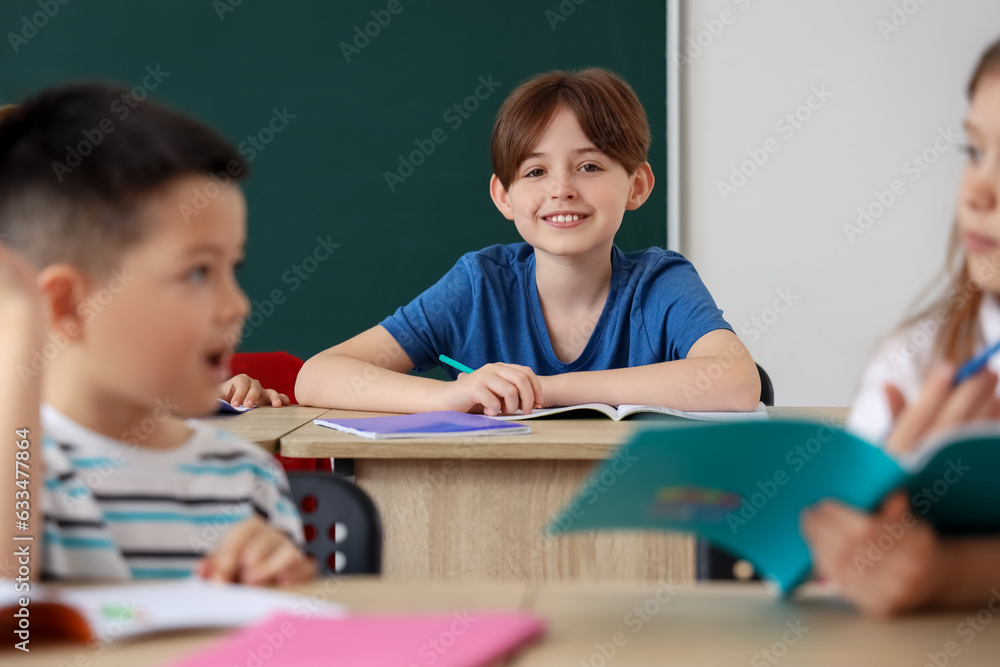 Little schoolboy having lesson in classroom