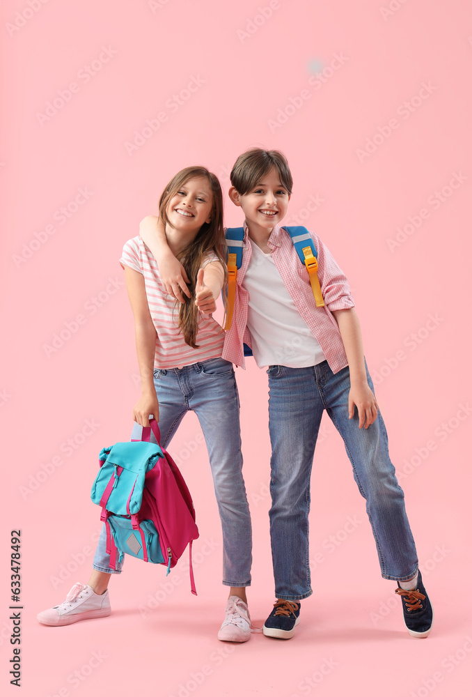 Little pupils with backpacks hugging on pink background