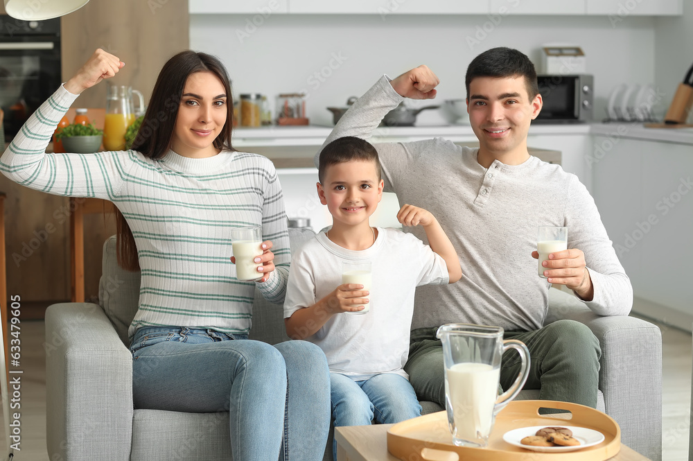 Happy family with glasses of milk showing muscles at home