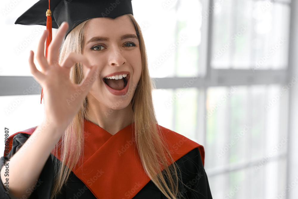 Female graduate student showing OK near window in room, closeup