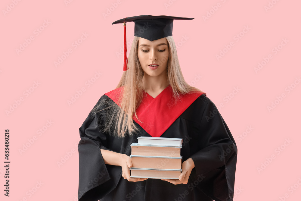 Female graduate student with books on pink background