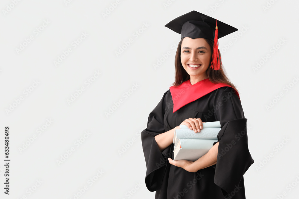 Female graduate student with books on light background