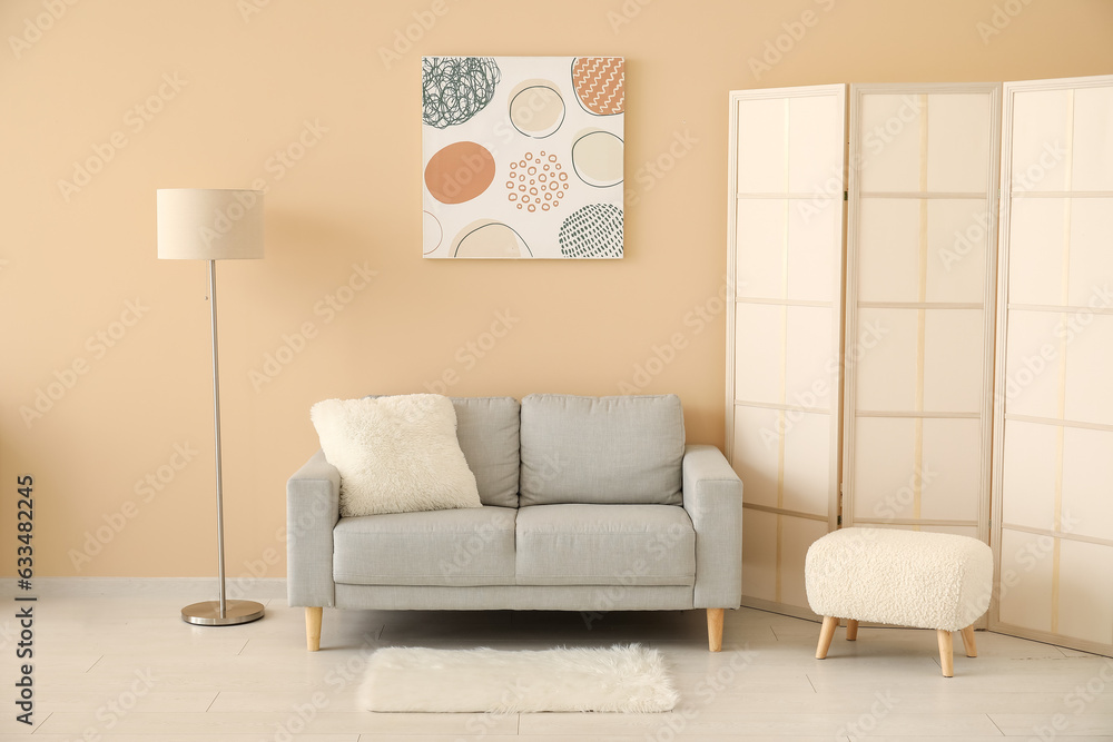 Interior of living room with grey sofa, folding screen and painting