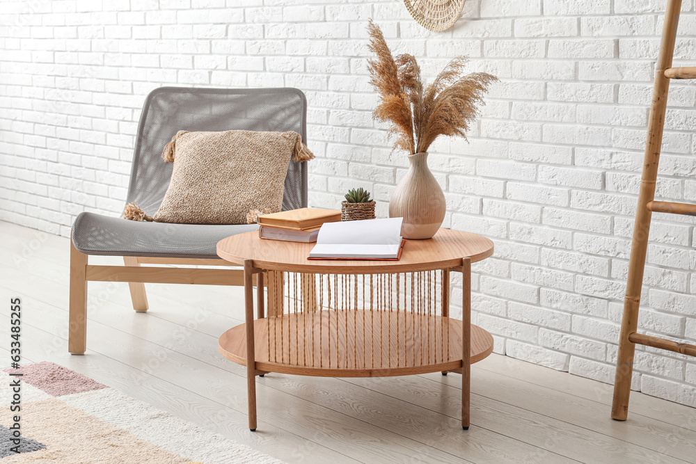 Light wooden coffee table with armchair and ladder near white brick wall