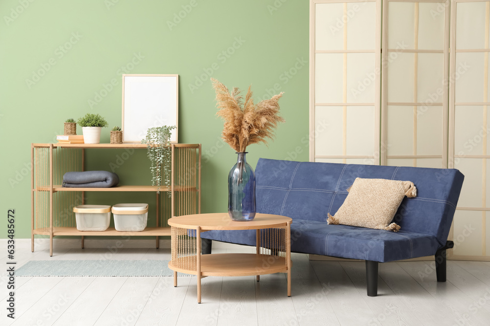 Wooden coffee table with shelving unit and couch near green wall