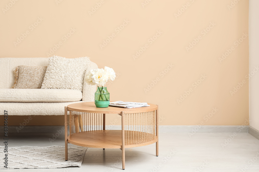 Wooden coffee table with couch and pillows near beige wall