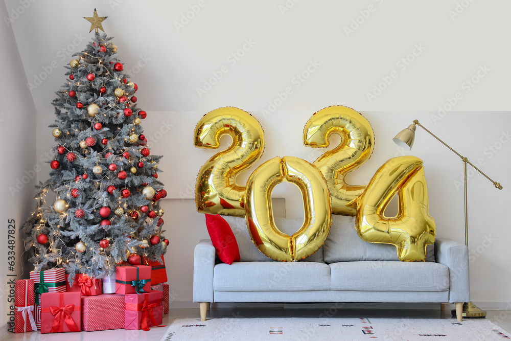 Balloons in shape of figure 2024 on grey sofa in living room with Christmas decor