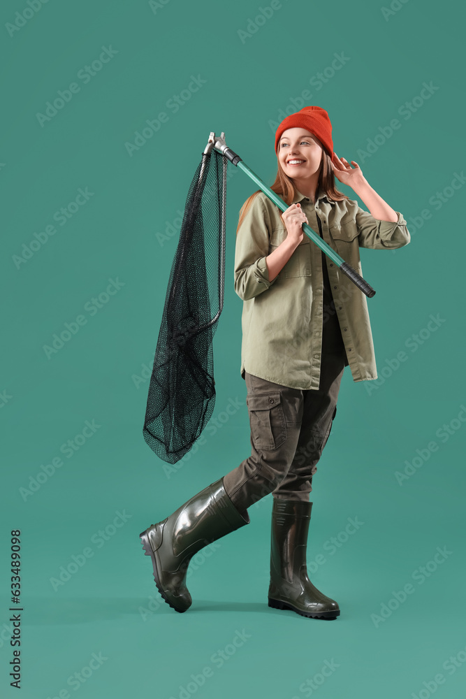 Happy young fisherwoman with landing net on green background