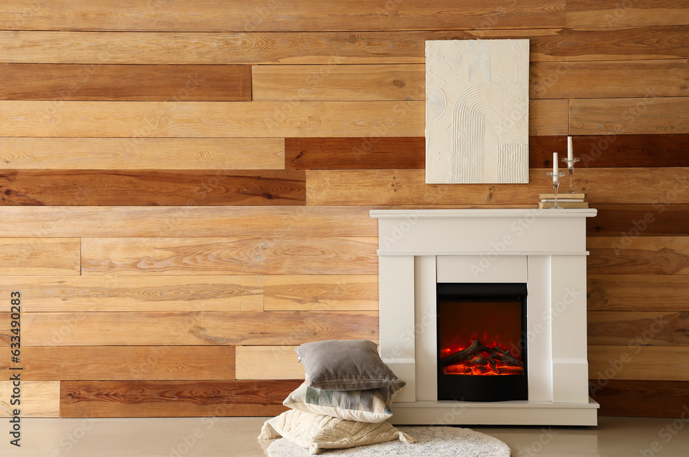 Stylish fireplace and soft pillows near wooden wall