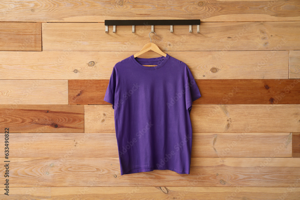 Stylish purple t-shirt hanging on wooden background