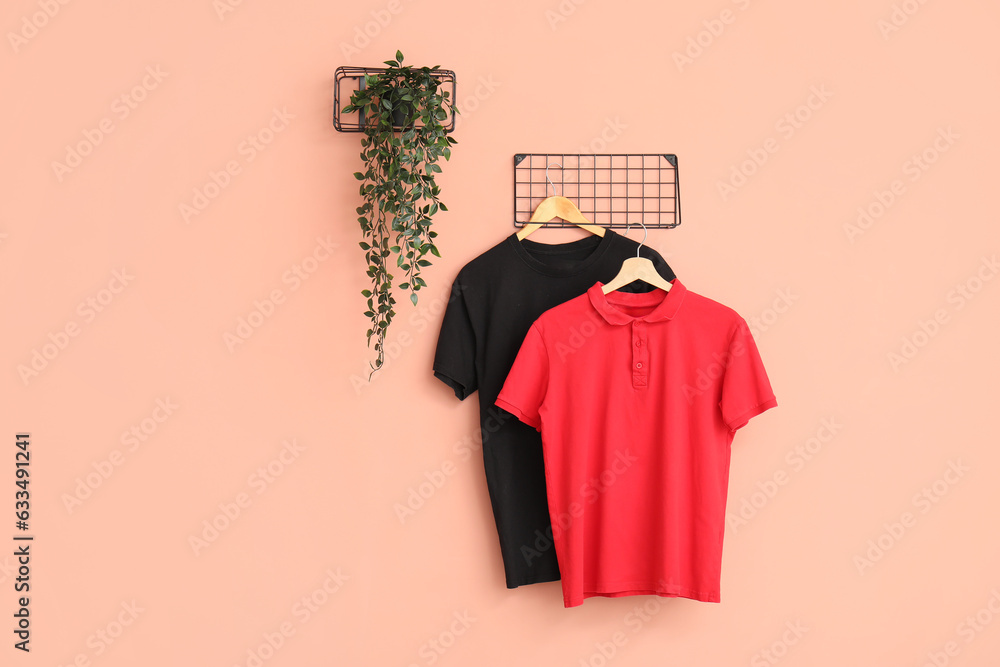 Stylish t-shirts hanging on pink background