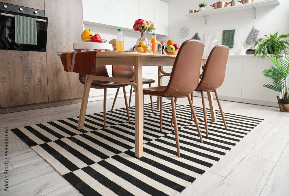 Served dining table on stylish carpet in modern kitchen