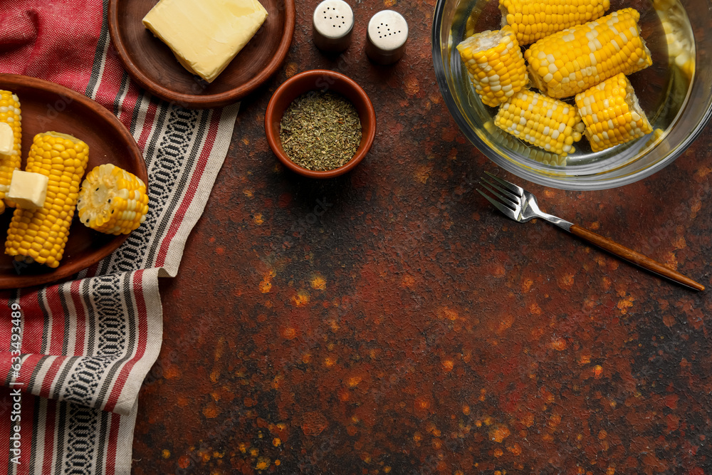 Plate of boiled corn cobs with butter on dark background