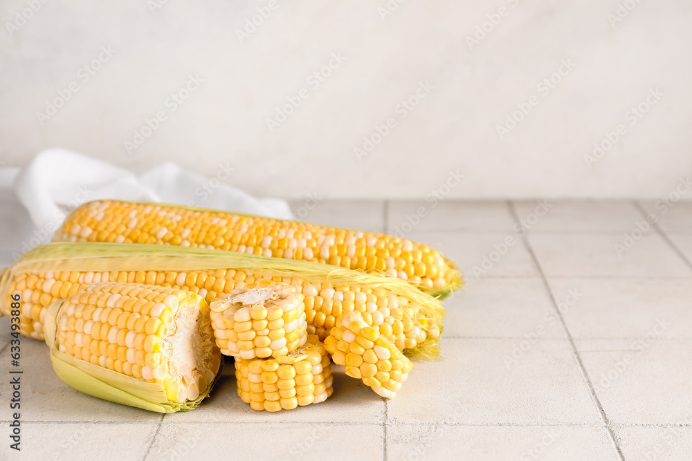 Fresh corn cobs on white tile table