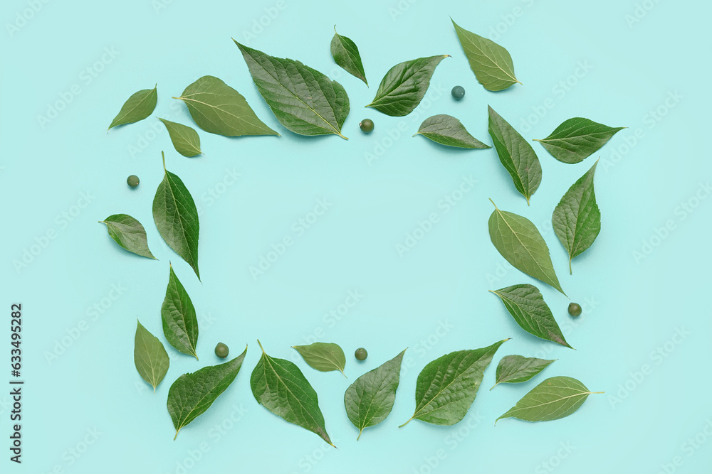 Frame made of green plant leaves and seeds on color background