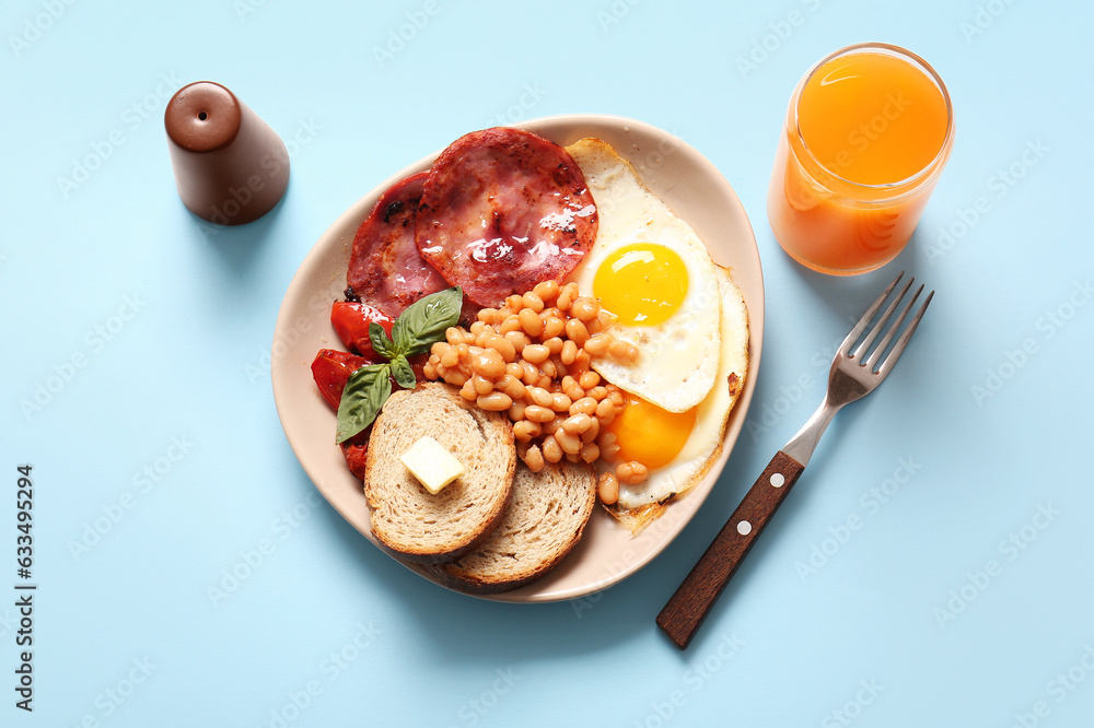 Plate with tasty English breakfast and glass of juice on blue background