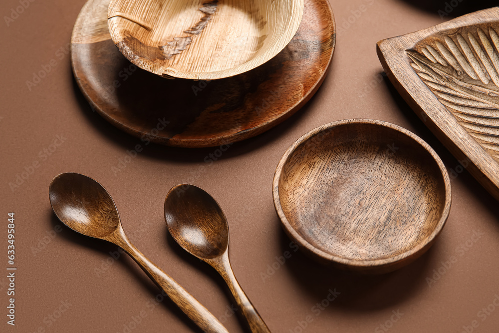 Different wooden tableware on brown background, closeup