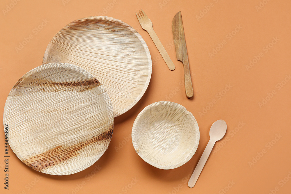 Wooden plates, bowl and cutlery on beige background