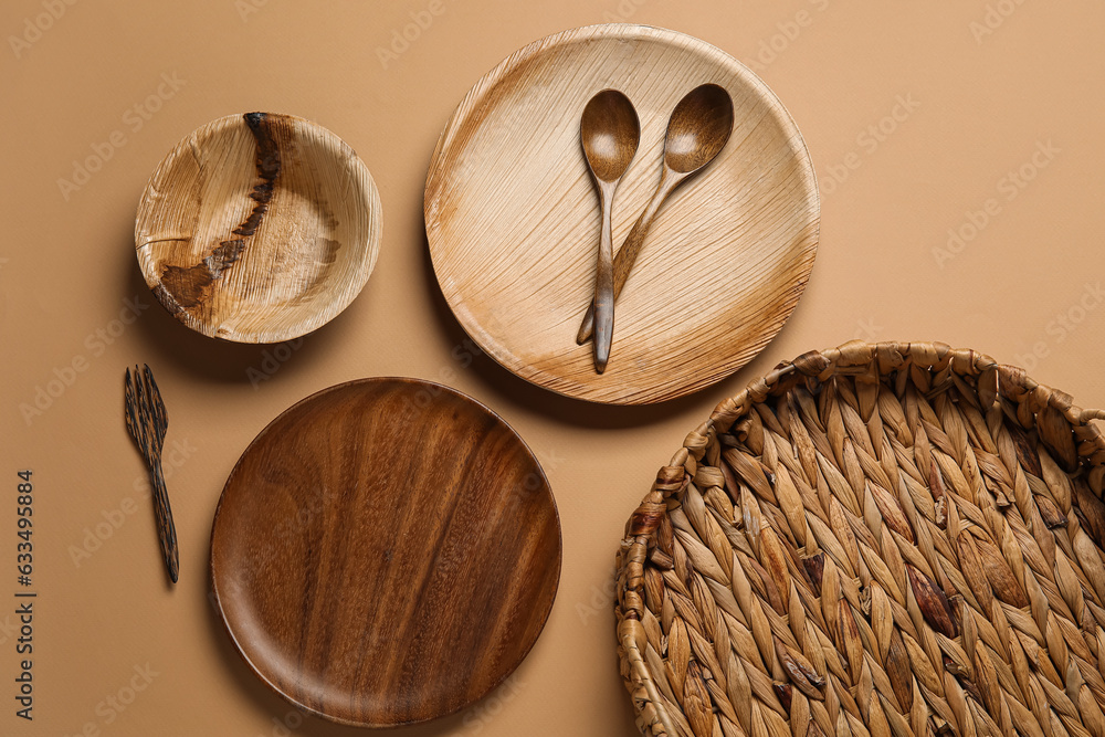 Different wooden tableware on beige background