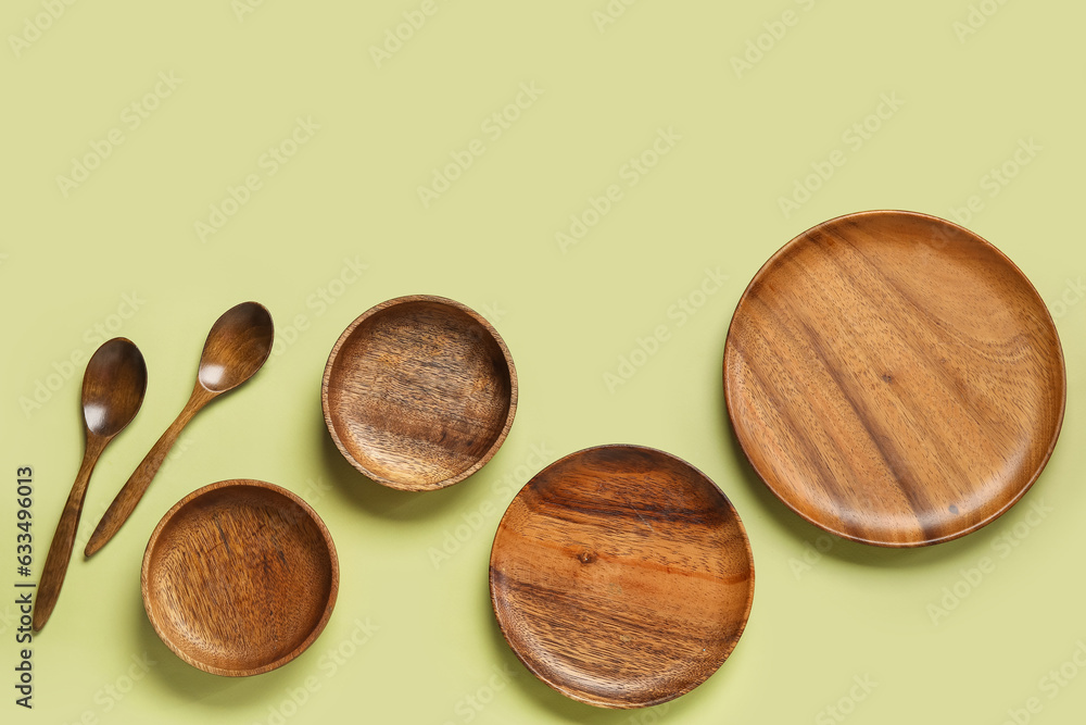 Wooden plates and spoons on green background