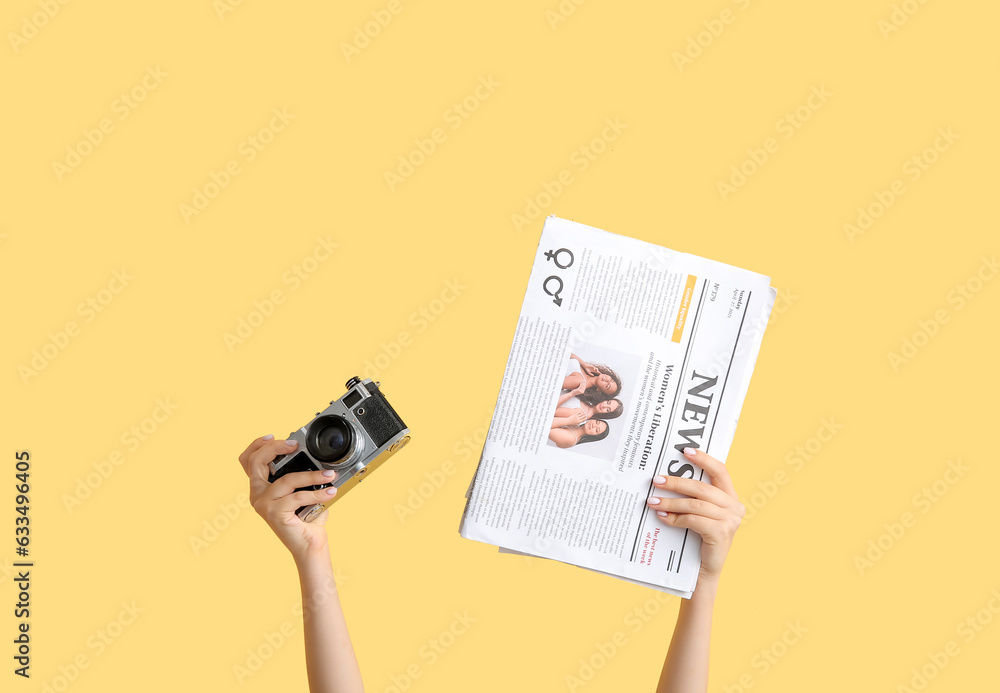 Female hands with photo camera and newspaper on color background