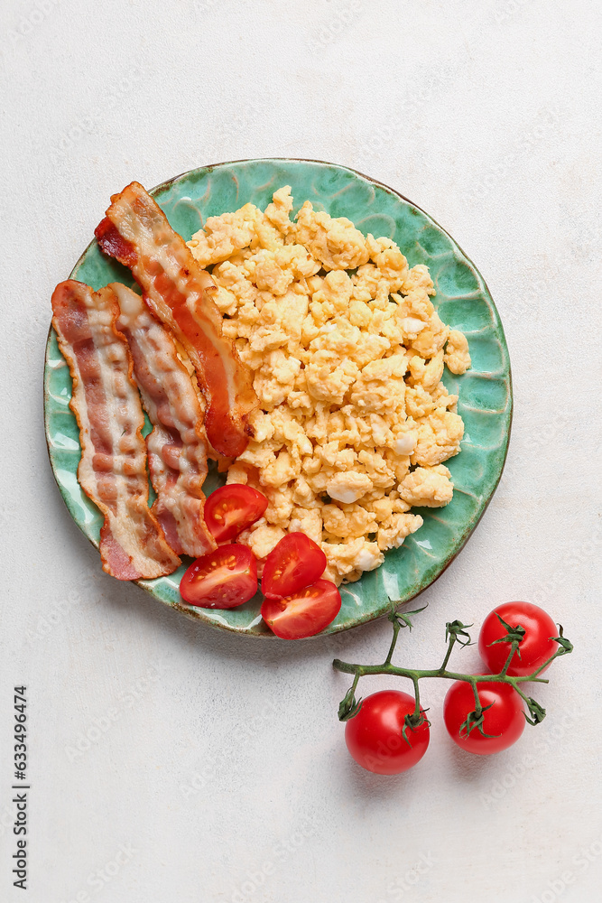 Plate of tasty scrambled eggs with bacon on light background