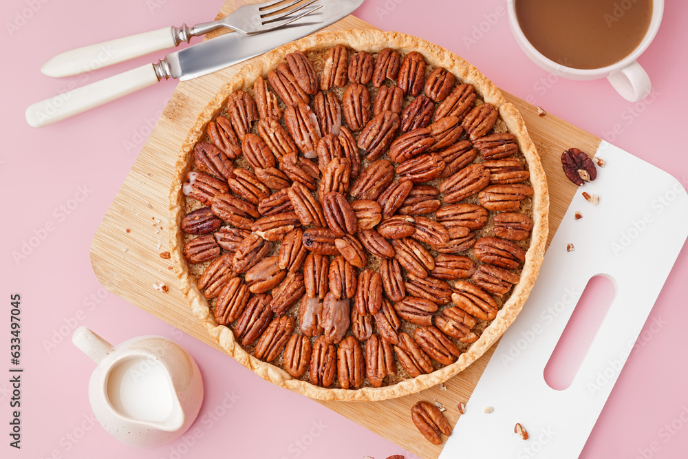 Wooden board with tasty pecan pie on pink background