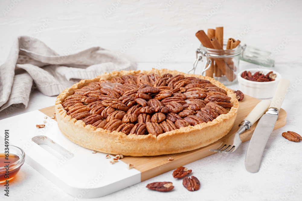 Wooden board with tasty pecan pie on light background