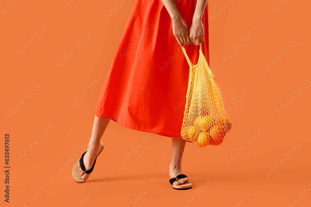 Beautiful woman in summer clothes and with eco bag on orange background