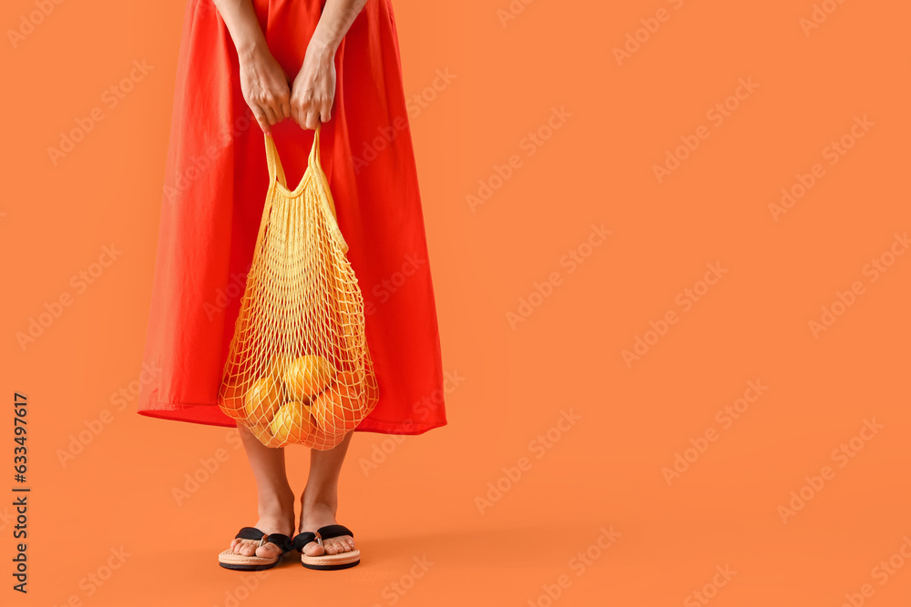 Beautiful woman in summer clothes and with eco bag on orange background