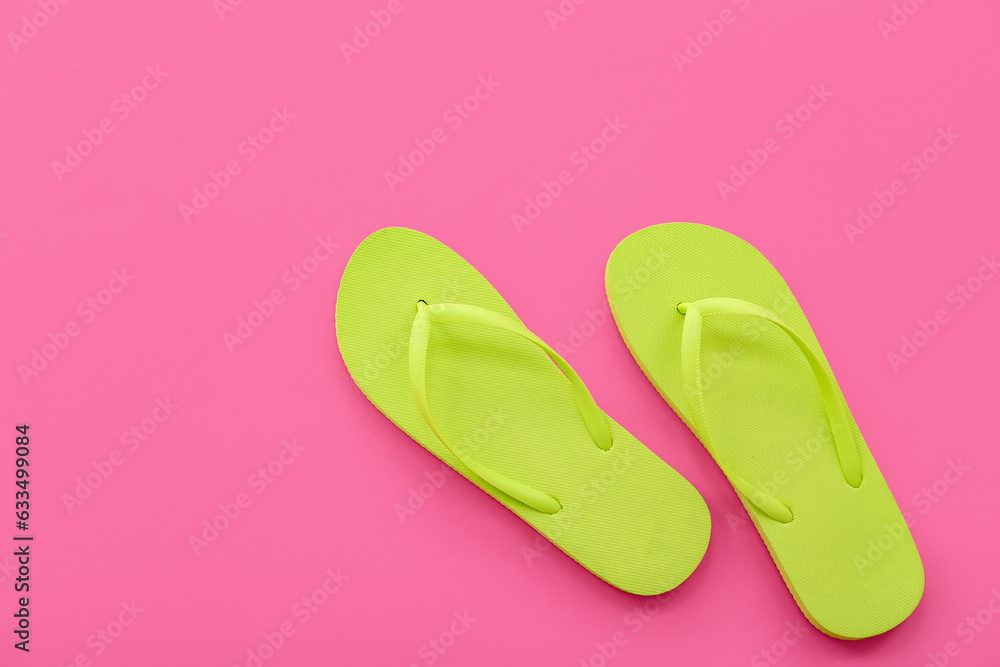 Pair of green flip flops on pink background