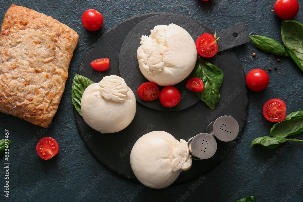 Board of tasty Burrata cheese with basil and tomatoes on dark background