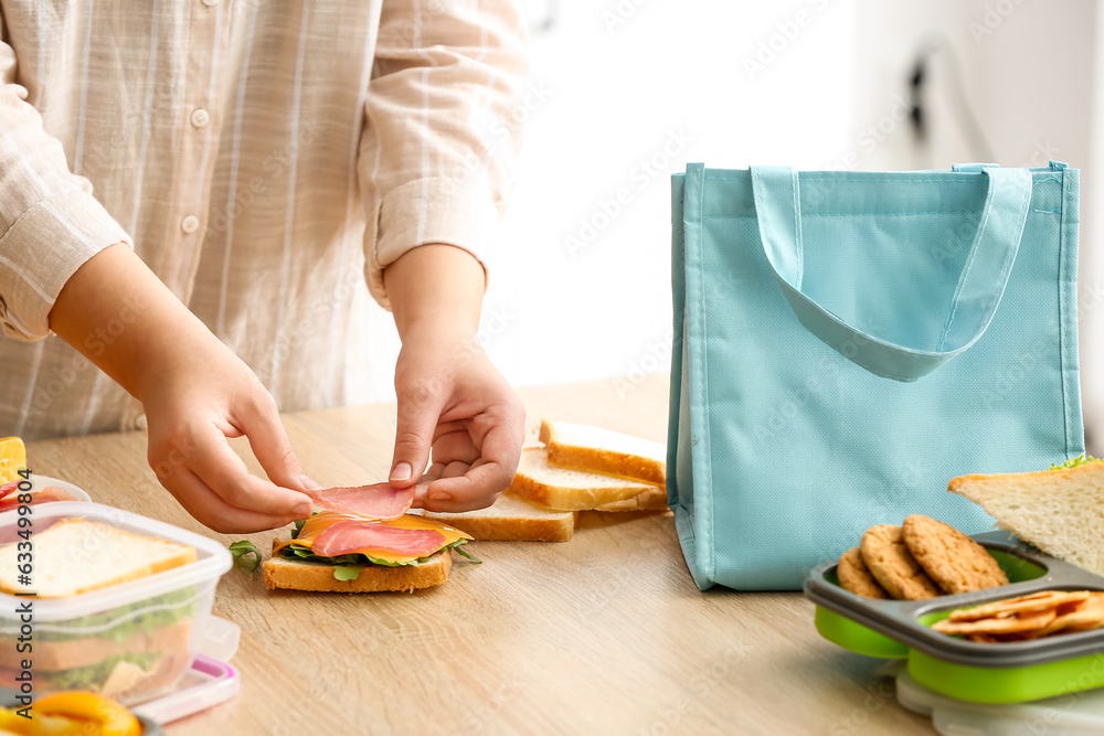 Mother making sandwiches for school lunch on table at kitchen