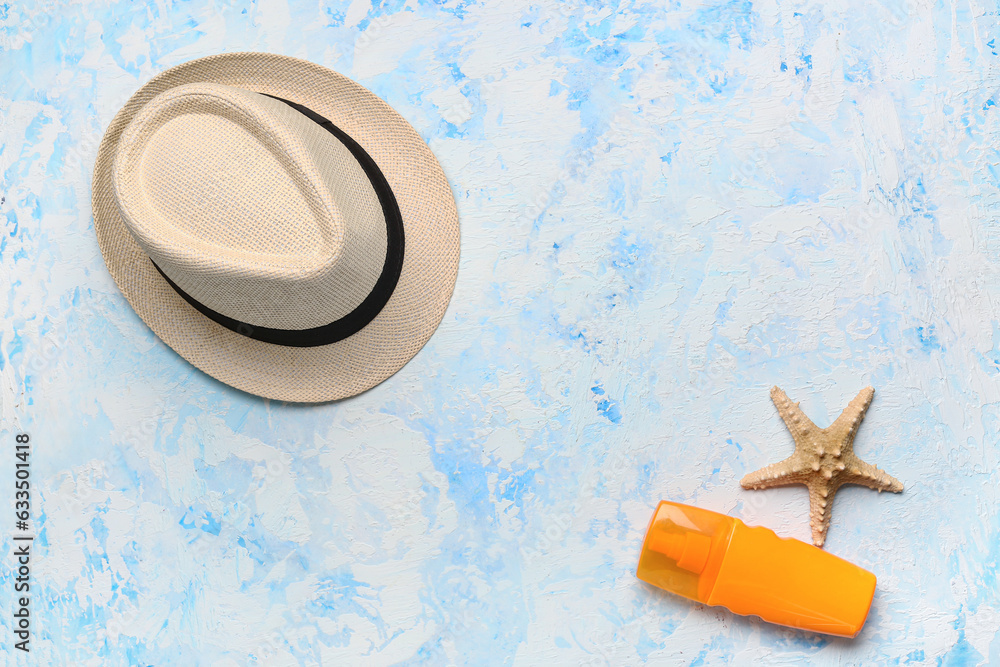 Stylish hat, bottle of sunscreen cream and starfish on color background